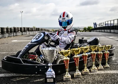 Ethan sat in his kart, number 99, posing with trophies.